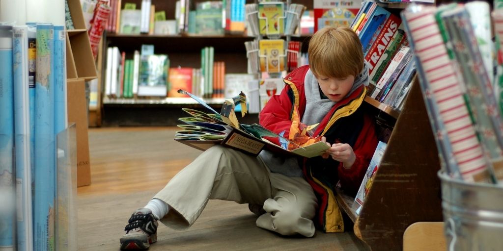 Child reading, surrounded by classic children's books